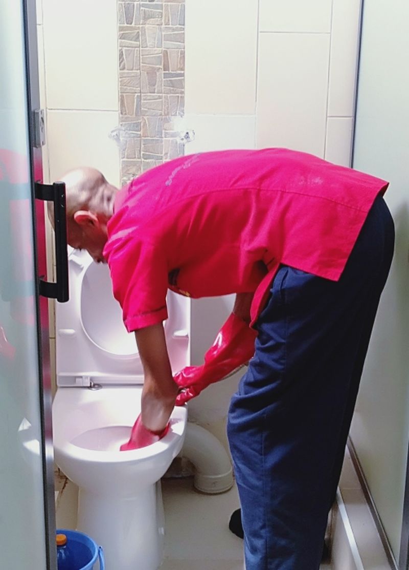 Cleaner sanitising an office kitchenette counter