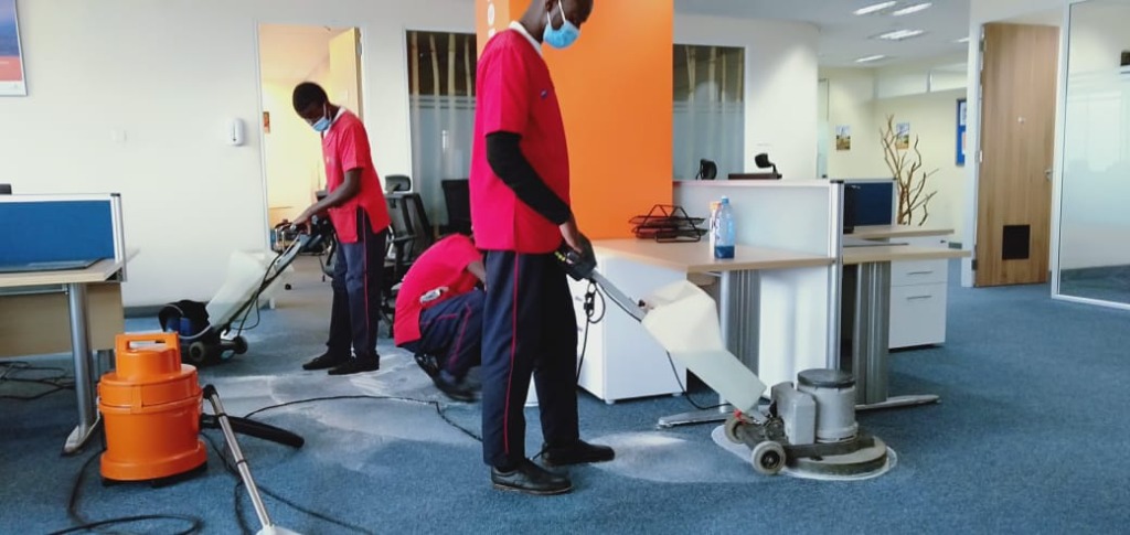 Team cleaning an open-plan office with industrial equipment